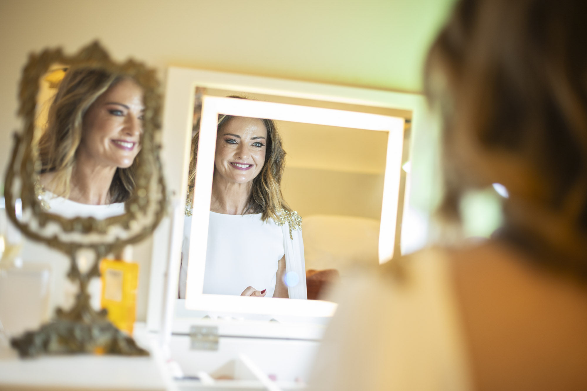 Novia sonriente frente al espejo en los preparativos de boda